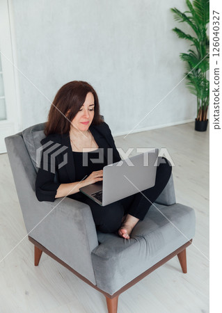 woman working on chair with laptop online from home 126040327