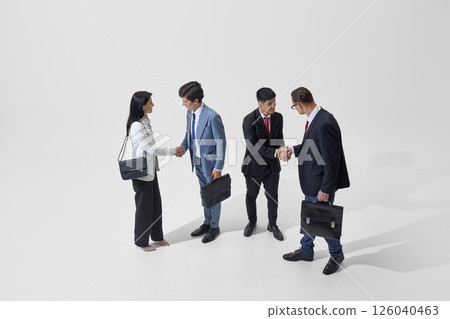 Colleagues shake hands against white studio background, representing diplomatic agreements and business partnerships in action. 126040463