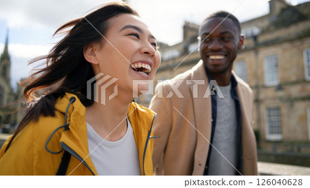 Friends Enjoy a Sunny Day Outdoors, Laughing and Walking Through a Historic City Street in Springtime 126040628