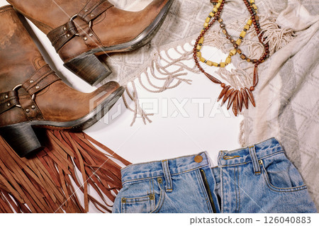 Boho Style. Leather Boots, Wooden Necklace, Denim Shorts and Hippie Bag with Fringe on White Background. Overhead View of Woman's Casual Day Outfits. Trendy Hipster Look. Boho Style. Leather Boots, Wooden Necklace, Denim Shorts and Hippie Bag with Fringe on White Background. Overhead View of Woman's Casual Day Outfits. Trendy Hipster Look. 126040883