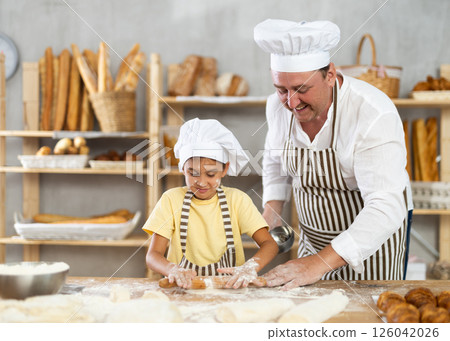 Little daughter and father make dough together in bakery kitchen 126042026