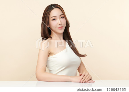 A beautiful young Asian woman with clean, fresh skin against a beige background. Skincare, facial treatment, cosmetology, beauty, and spa. An elegant portrait of an Asian woman. A beautiful young Asian woman with clean, fresh skin against a beige background. Skincare, facial treatment, cosmetology, beauty, and spa. An elegant portrait of an Asian woman. 126042565