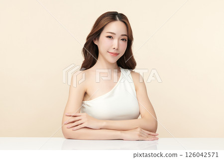 A beautiful young Asian woman with clean, fresh skin against a beige background. Skincare, facial treatment, cosmetology, beauty, and spa. An elegant portrait of an Asian woman. A beautiful young Asian woman with clean, fresh skin against a beige background. Skincare, facial treatment, cosmetology, beauty, and spa. An elegant portrait of an Asian woman. 126042571