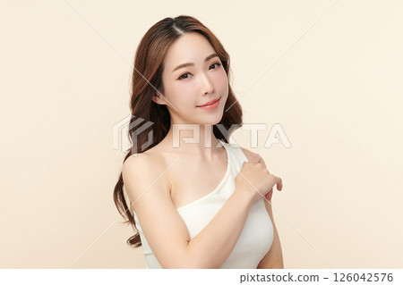A beautiful young Asian woman with clean, fresh skin against a beige background. Skincare, facial treatment, cosmetology, beauty, and spa. An elegant portrait of an Asian woman. A beautiful young Asian woman with clean, fresh skin against a beige background. Skincare, facial treatment, cosmetology, beauty, and spa. An elegant portrait of an Asian woman. 126042576
