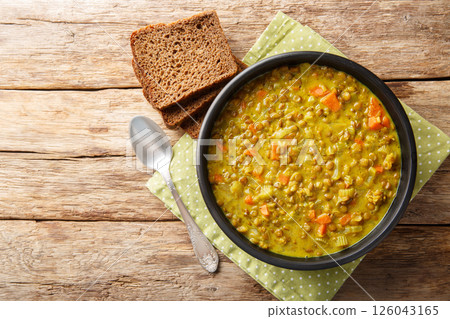 Thick healthy green lentil soup with coconut milk, carrot, onion, turmeric, lemon and ginger close-up in a plate. Horizontal top view Thick healthy green lentil soup with coconut milk, carrot, onion, turmeric, lemon and ginger close-up in a plate. Horizontal top view 126043165