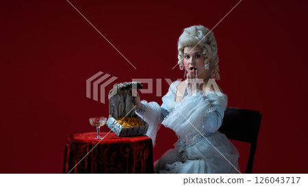 Hidden treasure. Female character in historical rococo look discovering chips in fancy chest, surprised expression. Hidden treasure. Female character in historical rococo look discovering chips in fancy chest, surprised expression. 126043717