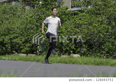 A young man running along the bank of the Tama River 126043751