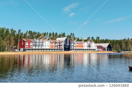 Colorful Scandinavian style homes on the shores of a lake, surrounded by pine trees, on a sunny summer day 126043860