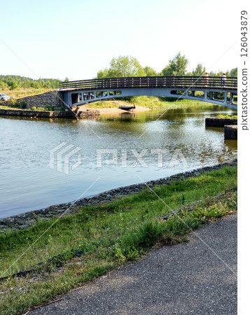 A small iron bridge over a river in the countryside on a sunny summer day, vertical 126043879