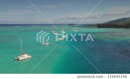 Stunning aerial view of sailboats and catamarans anchoring in turquoise waters near tropical island in Tahiti, French Polynesia, picturesque scene of paradise. Remote wild nature exotic summer travel 126045146