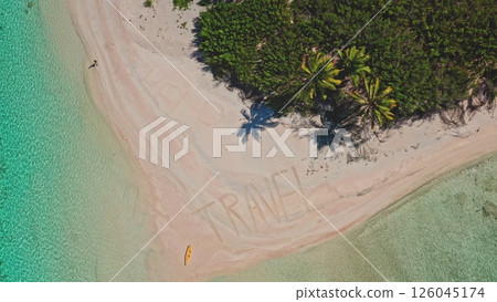 Aerial view of a tropical island with the word travel written in the sand of a pristine beach with turquoise water, palm trees and lush vegetation promoting tourism 126045174
