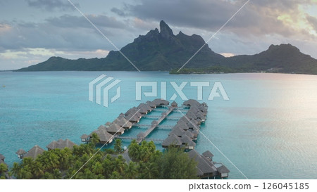 Breathtaking aerial beauty of Bora Bora, luxurious overwater bungalows line turquoise lagoon beneath the striking mount Otemanu at sunset. Remote wild nature paradise, exotic summer travel background Breathtaking aerial beauty of Bora Bora, luxurious overwater bungalows line turquoise lagoon beneath the striking mount Otemanu at sunset. Remote wild nature paradise, exotic summer travel background 126045185
