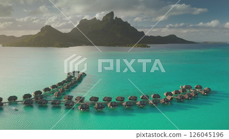 Stunning drone footage overwater bungalows lining a vibrant turquoise lagoon, mount Otemanu rising majestically in background, tropical paradise in Bora Bora. Travel exotic landscape vacation concept Stunning drone footage overwater bungalows lining a vibrant turquoise lagoon, mount Otemanu rising majestically in background, tropical paradise in Bora Bora. Travel exotic landscape vacation concept 126045196