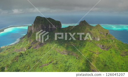 Aerial perspective showcases an island's vibrant green mountains surrounded by stunning turquoise lagoons, revealing a serene coastal community and intricate landscapes 126045207