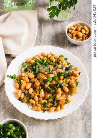 Homemade fried white beans and greens salad on plate on table vertical view 126045824