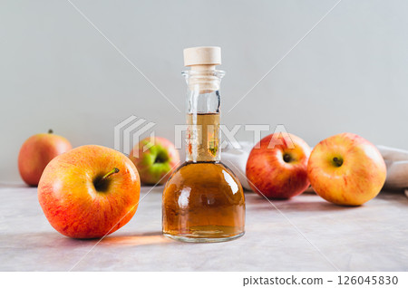 Apple cider vinegar in a bottle and fresh apples on the table Apple cider vinegar in a bottle and fresh apples on the table 126045830