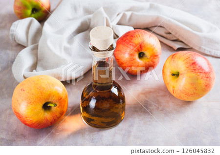 Fermented apple cider vinegar in glass bottle and fruits on table 126045832