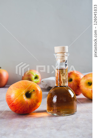 Apple cider vinegar in a bottle and fresh apples on the table vertical view 126045833