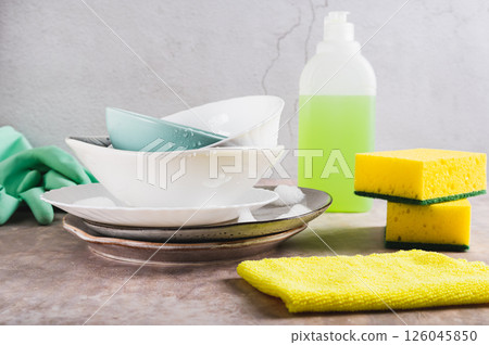 Stack of plates in foam, cloth, sponges, gloves and detergent on table Stack of plates in foam, cloth, sponges, gloves and detergent on table 126045850