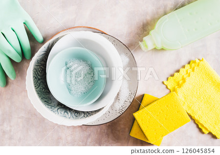 Stack of plates in foam, cloth, sponges, gloves and detergent on table top view Stack of plates in foam, cloth, sponges, gloves and detergent on table top view 126045854