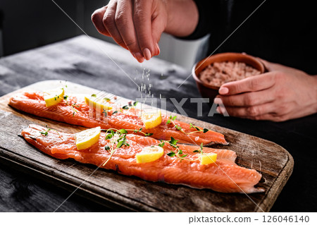 Girl Adding A Pinch Of Salt To Raw Red Trout Fish Girl Adding A Pinch Of Salt To Raw Red Trout Fish 126046140