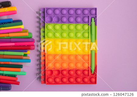 Pencil case with school supplies with notebook on purple background. Top view. Copy space Pencil case with school supplies with notebook on purple background. Top view. Copy space 126047126