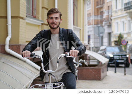 Handsome bike messenger with backpack stands near bicycle and look at camera 126047623