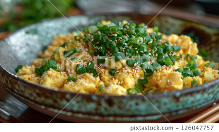 In an elegant and minimalist bowl, scrambled eggs are cooked with a hint of soy sauce, adding a subtle umami flavor 126047757