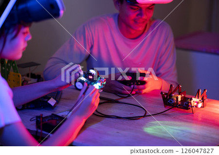 Young man and young woman amateur inventor testing electronic device 126047827