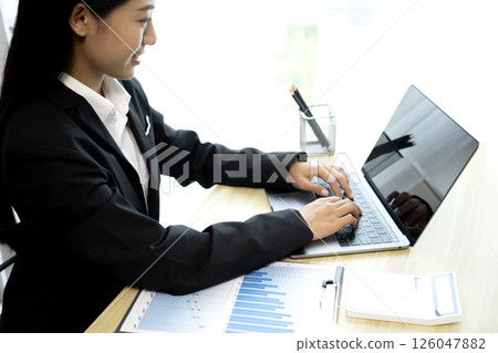 A businesswoman is focusing on laptop keys on her desk A businesswoman is focusing on laptop keys on her desk 126047882
