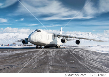 White wide body transport cargo aircraft at winter airport on the background of high snow capped mountains 126047883