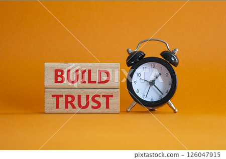 Build trust symbol. Wooden blocks with words Build trust. Beautiful orange background with alarm clock. Business and Build trust concept. Copy space. 126047915