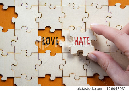 Love vs Hate symbol. Concept word Love vs Hate on wooden puzzle. Businessman hand. Beautiful orange background. Business and Love vs Hate concept. Copy space Love vs Hate symbol. Concept word Love vs Hate on wooden puzzle. Businessman hand. Beautiful orange background. Business and Love vs Hate concept. Copy space 126047981