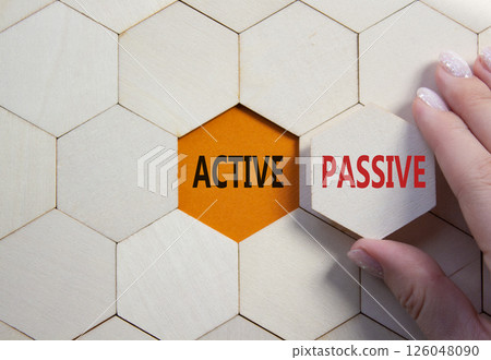 Active or Passive symbol. Concept word Active or Passive on wooden comb puzzle. Businessman hand. Beautiful orange background. Business and Active or Passive concept. Copy space Active or Passive symbol. Concept word Active or Passive on wooden comb puzzle. Businessman hand. Beautiful orange background. Business and Active or Passive concept. Copy space 126048090