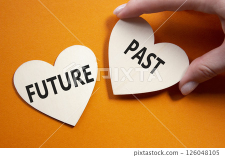 Future or Past symbol. Concept word Future or Past on wooden hearts. Businessman hand. Beautiful orange background. Business and Future or Past concept. Copy space Future or Past symbol. Concept word Future or Past on wooden hearts. Businessman hand. Beautiful orange background. Business and Future or Past concept. Copy space 126048105