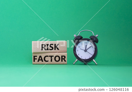 Risk Factor symbol. Wooden blocks with words Risk Factor Beautiful green background with alarm clock. Business and Risk Factor concept. Copy space. 126048116