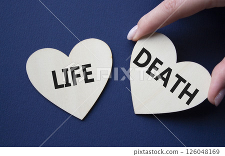 Life or Death symbol. Concept word Life or Death on wooden hearts. Businessman hand. Beautiful deep blue background. Business and Life or Death concept. Copy space 126048169