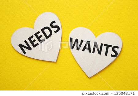 Wants and Needs symbol. Concept word Wants and Needs on wooden hearts. Beautiful yellow background. Business and Wants and Needs concept. Copy space 126048171