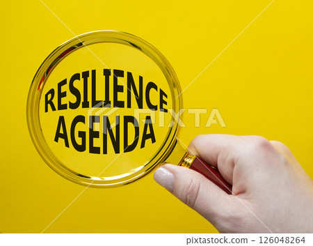 Resilience agenda symbol. Magnifying glass with words Resilience agenda. Beautiful yellow background. Businessman hand. Business and Resilience agenda concept. Copy space. Resilience agenda symbol. Magnifying glass with words Resilience agenda. Beautiful yellow background. Businessman hand. Business and Resilience agenda concept. Copy space. 126048264