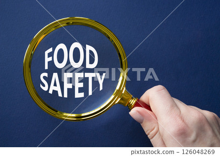 Food Safety symbol. Magnifying glass with words Food Safety. Beautiful deep blue background. Businessman hand. Business and Food Safety concept. Copy space. Food Safety symbol. Magnifying glass with words Food Safety. Beautiful deep blue background. Businessman hand. Business and Food Safety concept. Copy space. 126048269