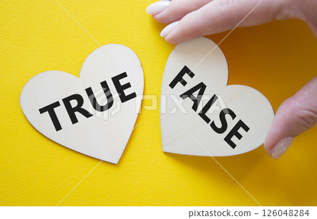 True or False symbol. Concept word True or False on wooden hearts. Businessman hand. Beautiful yellow background. Business and True or False concept. Copy space True or False symbol. Concept word True or False on wooden hearts. Businessman hand. Beautiful yellow background. Business and True or False concept. Copy space 126048284