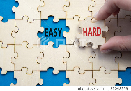 Easy or Hard symbol. Concept word Easy or Hard on wooden puzzle. Businessman hand. Beautiful blue background. Business and Easy or Hard concept. Copy space 126048299