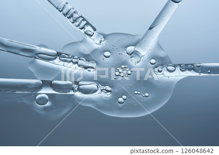 A large drop of hyaluronic serum for a blistered face and several pipettes on a blue background. 126048642