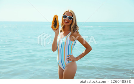 Summer, happy smiling young woman, laughing, with fruits, having fun on the beach on sea background Summer, happy smiling young woman, laughing, with fruits, having fun on the beach on sea background 126048888