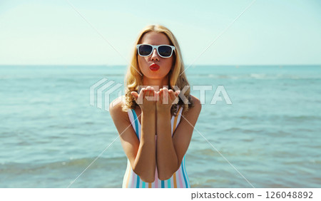 Summer vacation, beautiful young woman blowing kiss in swimsuit, sunglasses, on the beach on sea Summer vacation, beautiful young woman blowing kiss in swimsuit, sunglasses, on the beach on sea 126048892