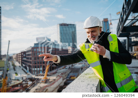 Site manager giving instructions over radio during building inspection. 126049394