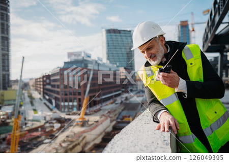 Site manager giving instructions over radio during building inspection. 126049395