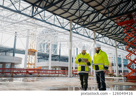 Construction managers using digital tablet on site, reviewing project plans. Construction managers using digital tablet on site, reviewing project plans. 126049416