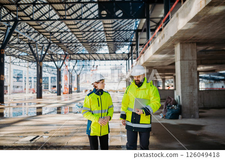 Engineers discussing construction plans using a tablet on site. Engineers discussing construction plans using a tablet on site. 126049418