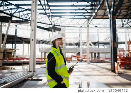 Construction foreman giving instructions over radio during building inspection. 126049422